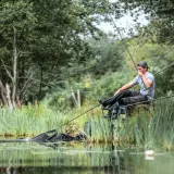 Wędkarz łowi rybę, która właśnie trafia do podbieraka. Dba o wymiar ochronny karpia, by mógł dalej rosnąć.