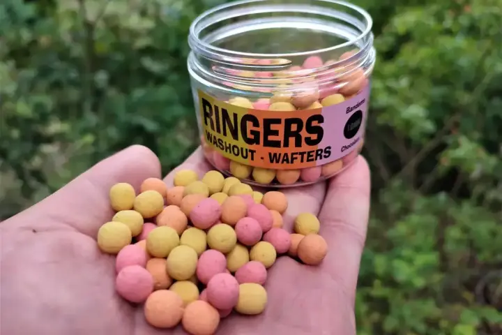 Kolorowe kulki zanętowe Ringers Washout - Wafters w dłoni, obok słoiczka. Idealne na połów.